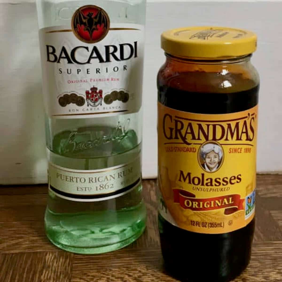 Bacardi Rum bottle and Grandma's Molasses jar on wood tile.