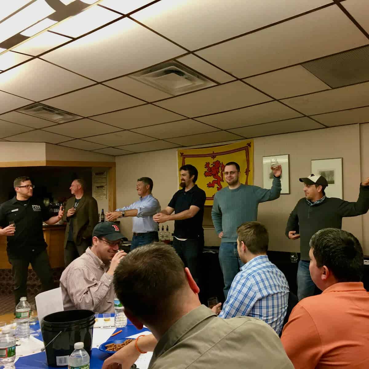 Men pantomiming whisky production in front of an audience.