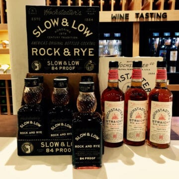 Hochstadter's Slow & Low lineup in bottles on a counter with the brand sign behind them.