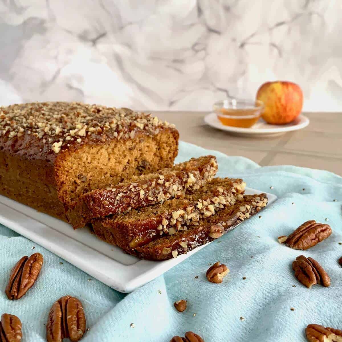 Sliced honey cake on a white platter with pecans.