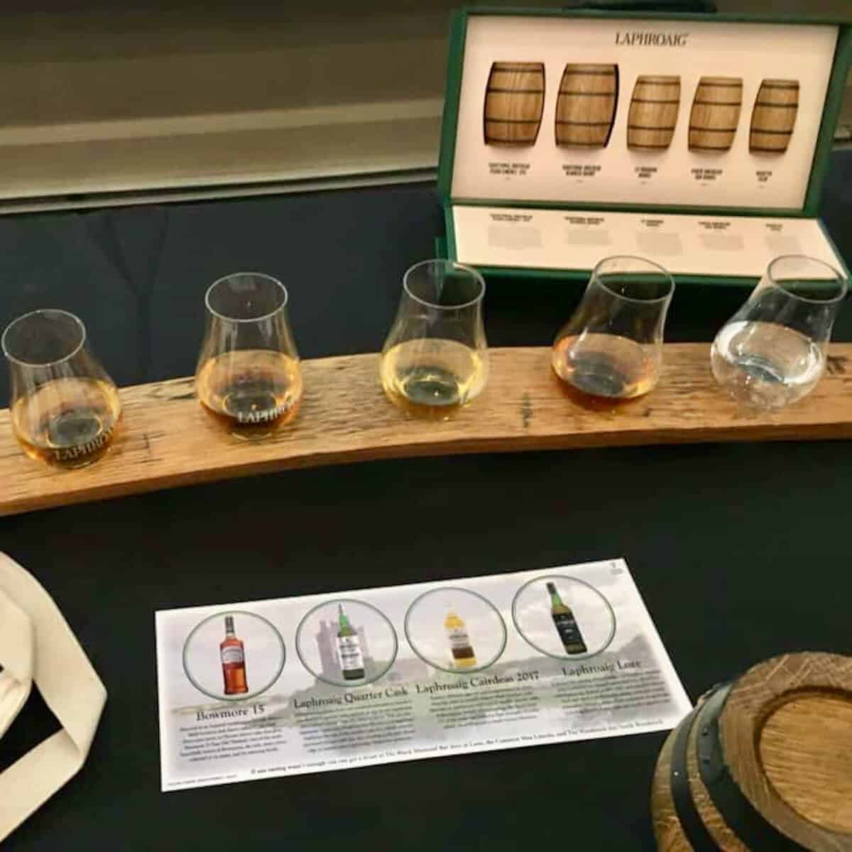 Laphroaig and Bowmore scotch tasting lineup poured in a flight on a table.