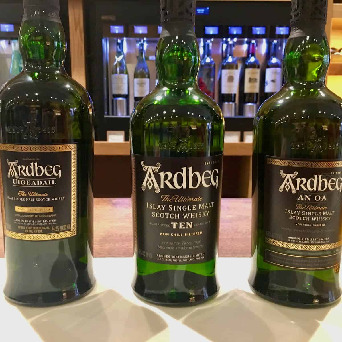 Ardbeg 10, Uigeadail, & An Oa lineup in bottles on a counter.