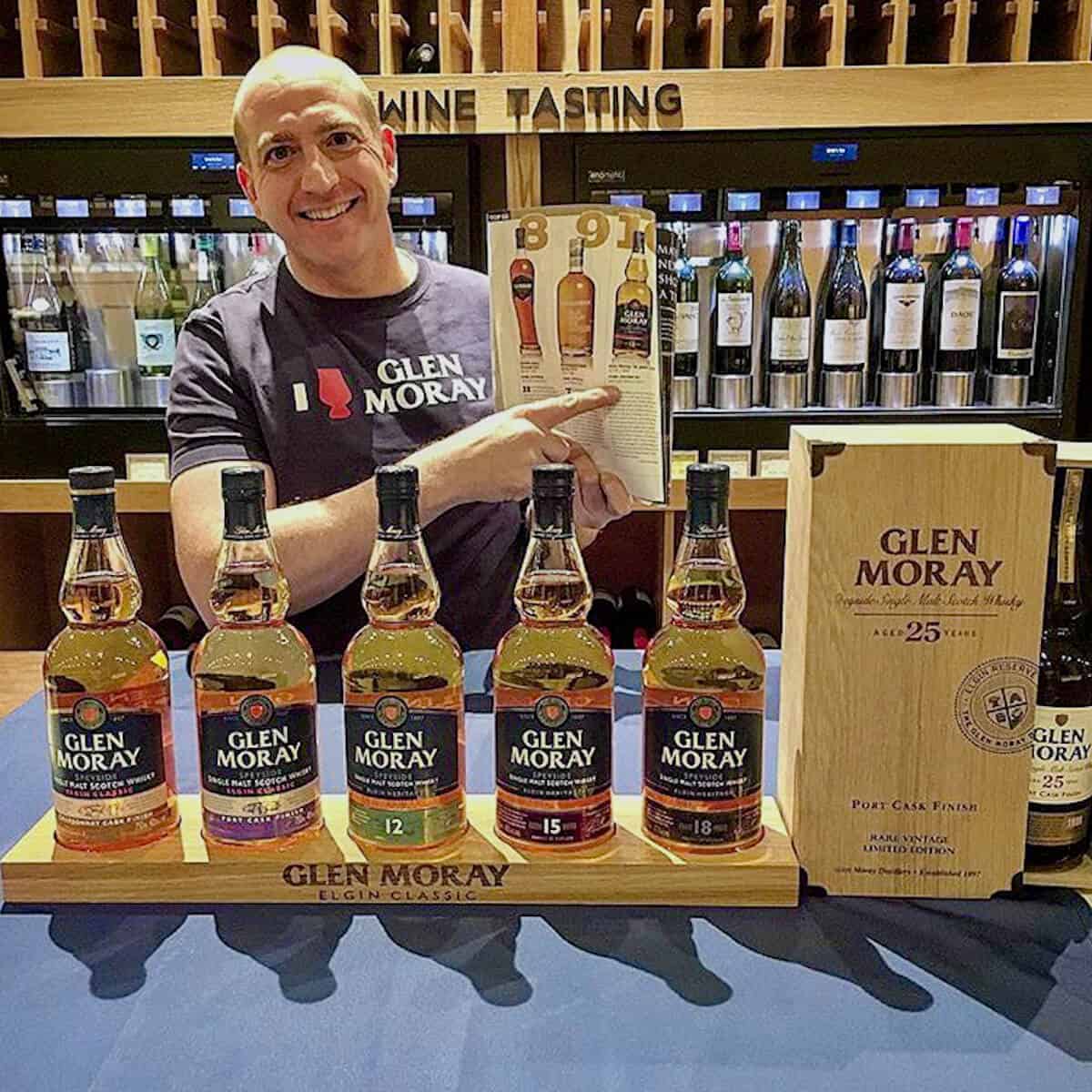 Glen Moray whisky bottle display with sales rep pointing to prochure behind.