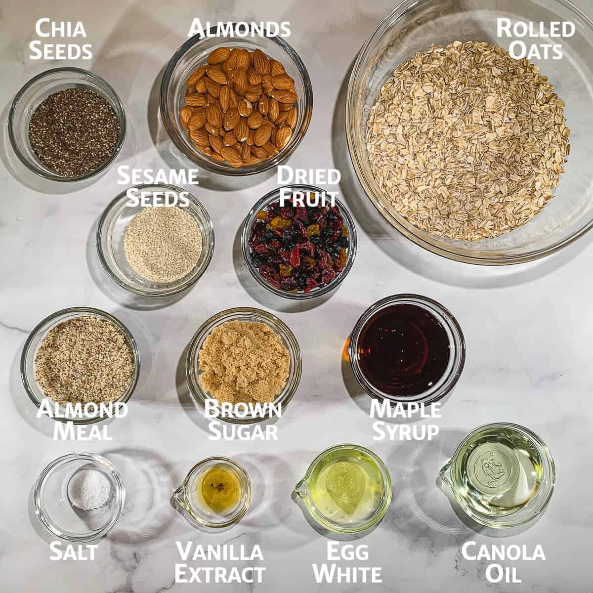 Granola ingredients portioned into glass bowls from overhead.