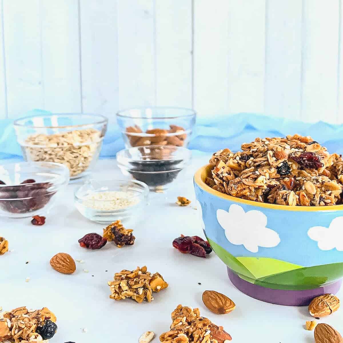 Granola in a bowl next to ingredients portioned into glass bowls.
