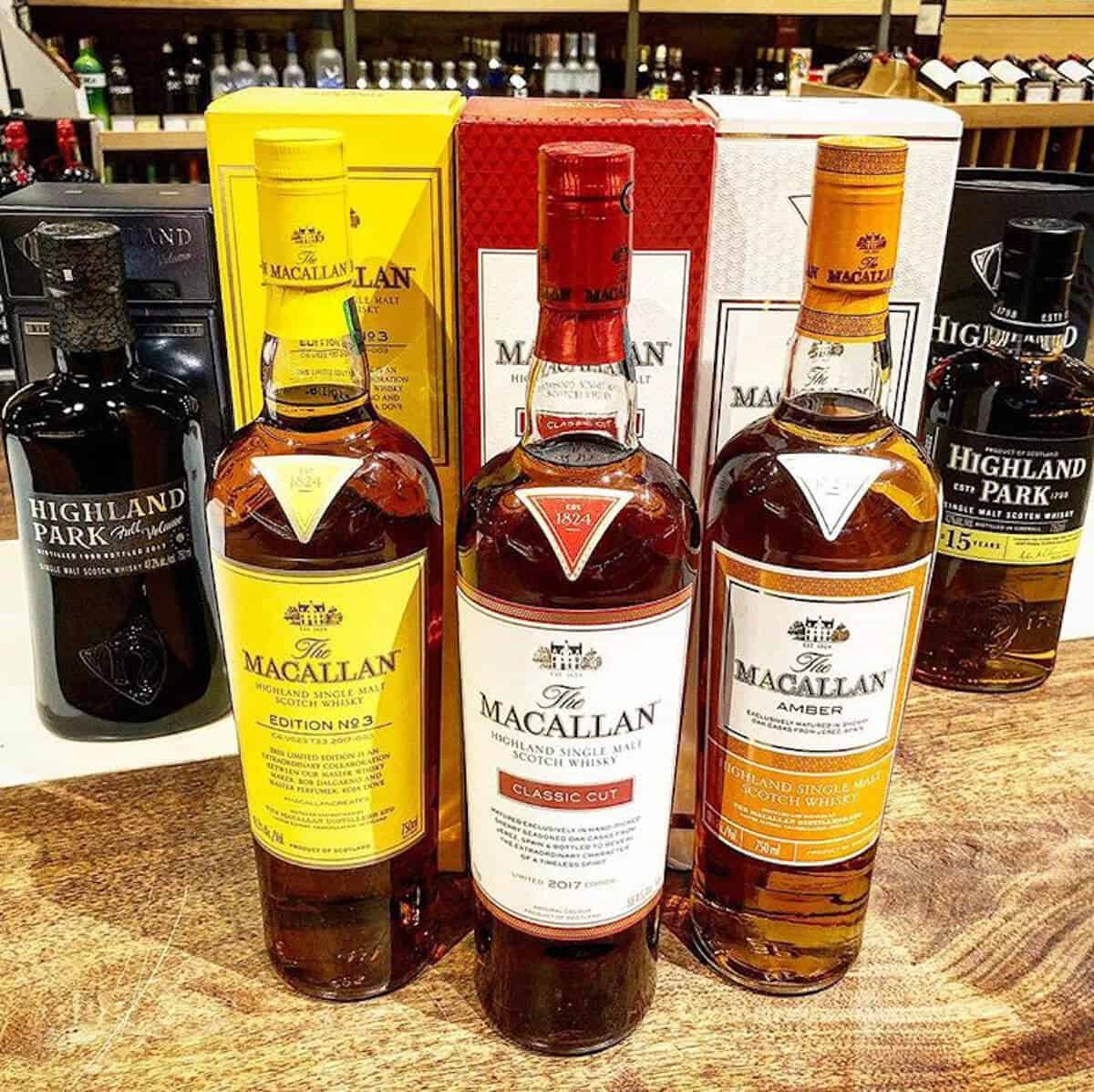 Macallan and Highland Park lineup in bottles on a table.