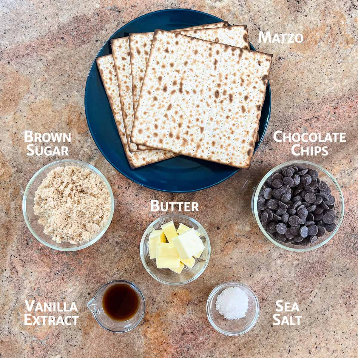 Matzo crack ingredients portioned into glass bowls with matzo on a blue plate.
