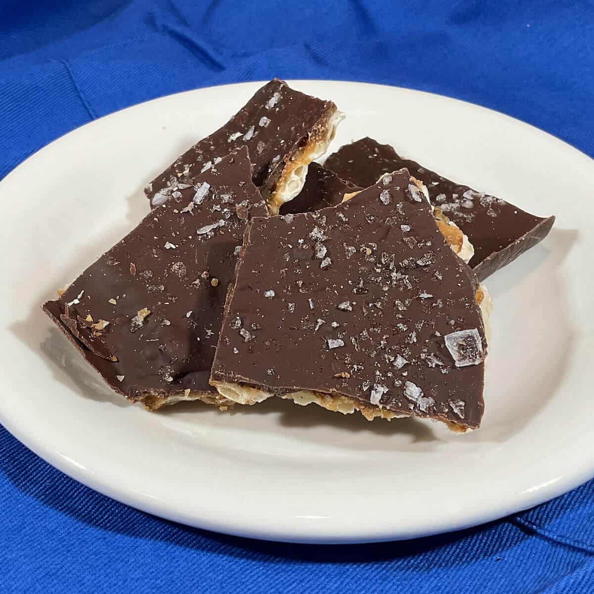 Matzo Crack broken on a white plate sitting on a blue apron.