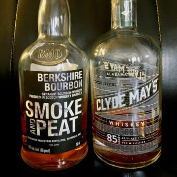 Berkshire Bourbon Smoke & Peat and Clyde Mays Alabama-style whiskey in bottles on a leather chair.
