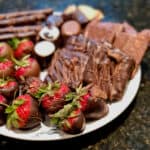 Plate of chocolate dipped treats on a white plate set on a black marble counter.