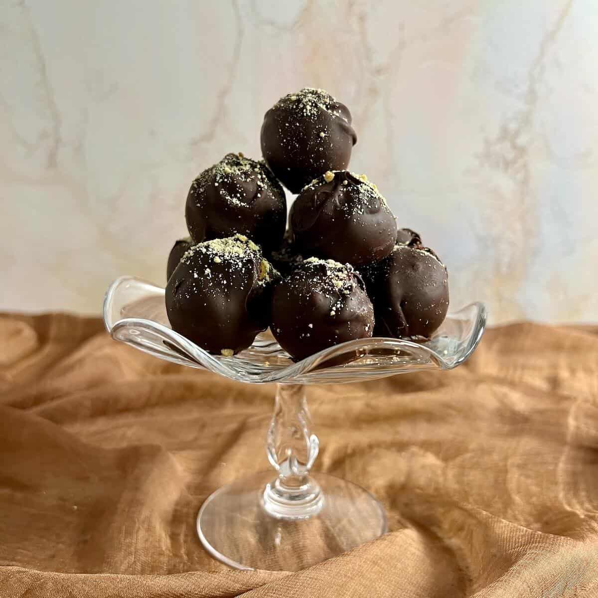 Tiramisu truffles stacked on a glass stand.