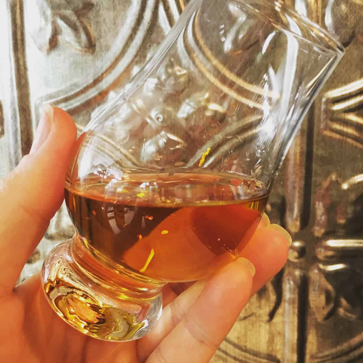 Four roses bourbon in a Glen Cairn glass held at an angle.