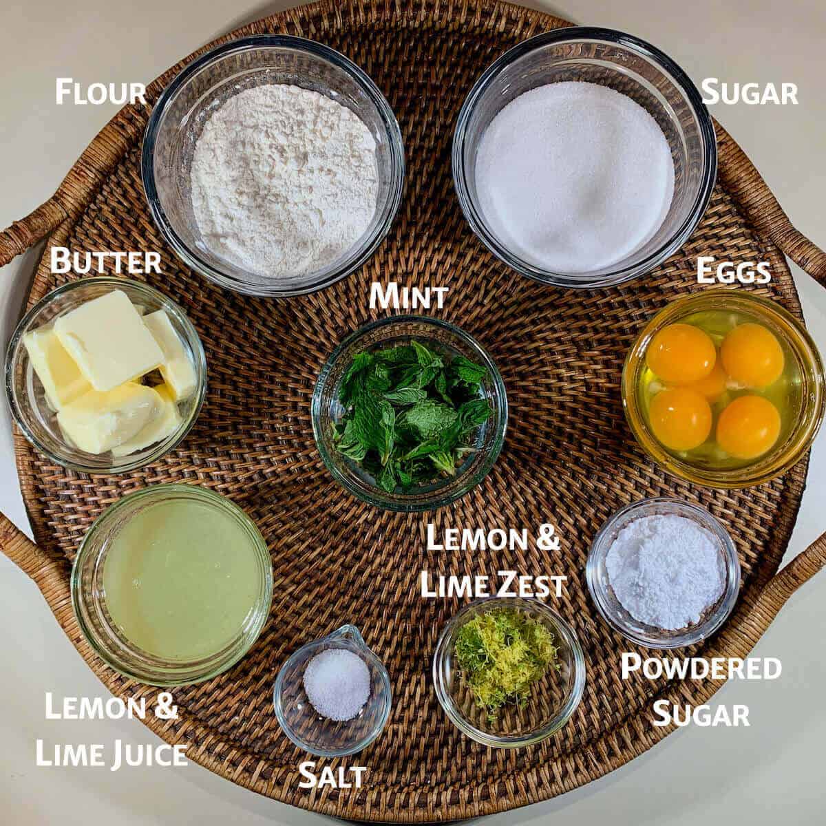 Mint Lemon Lime bar ingredients portioned in glass bowls on a woven tray.