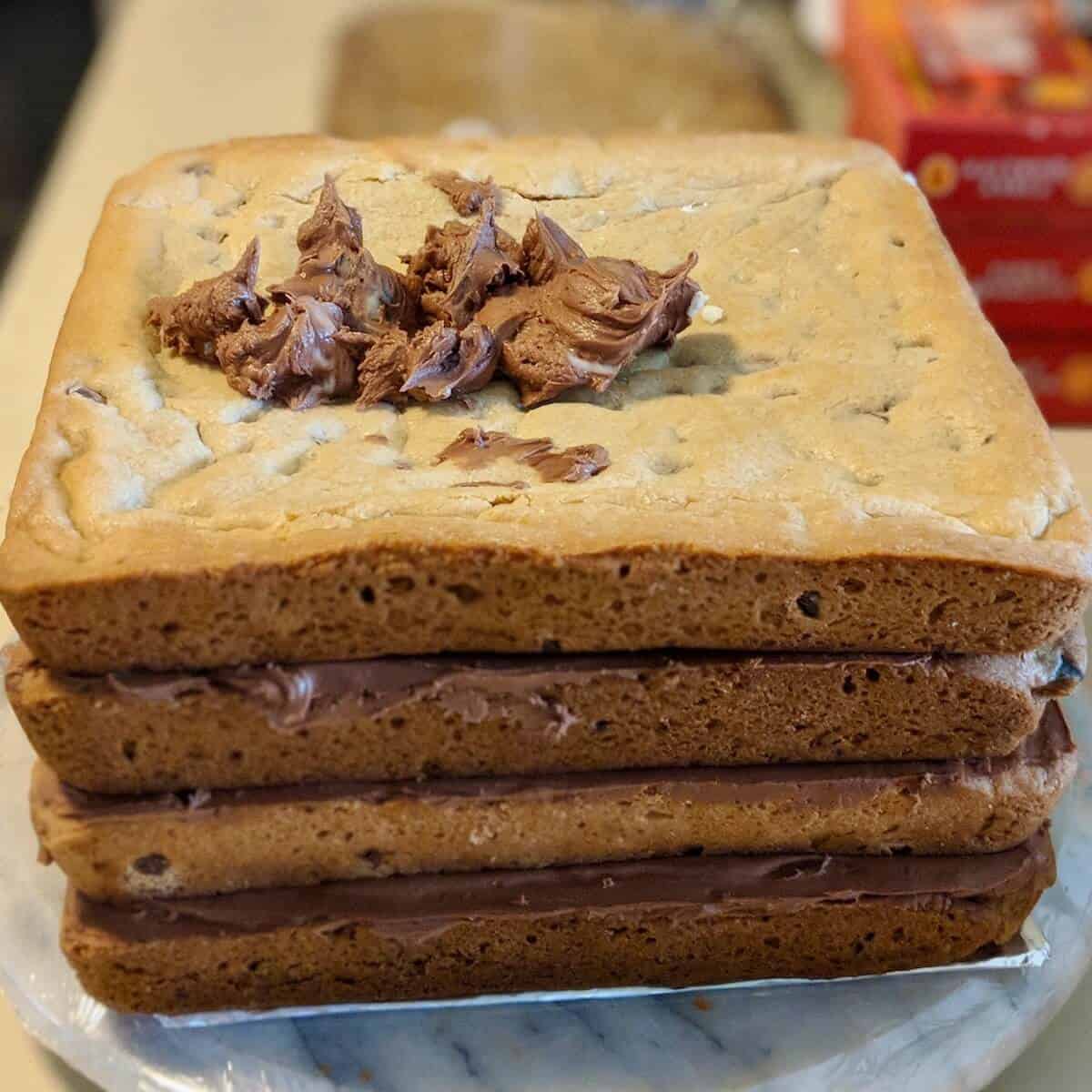 Chocolate Chip Cookie Cake stacked on a turntable with frosting.