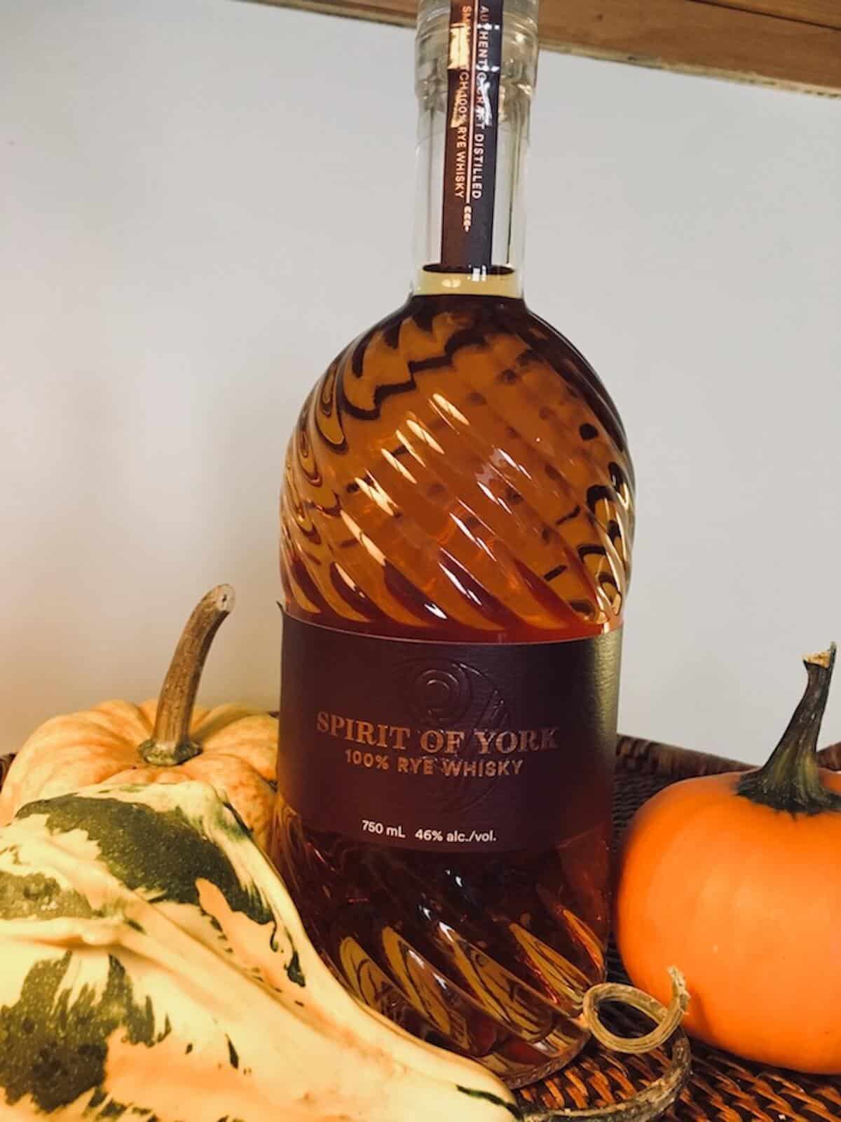 Spirit of York rye whisky bottle surrounded by gourds on a wood tray.Spirit of York rye whisky bottle surrounded by gourds on a wood tray.