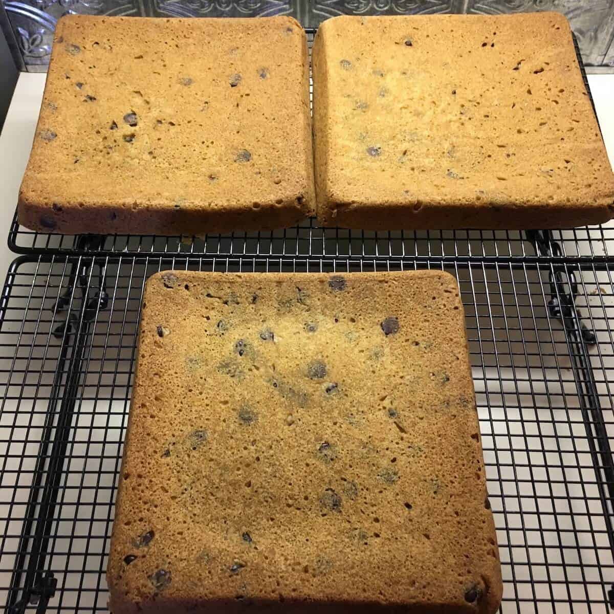Baked chocolate chip cookie cake layers cooling on a rack.