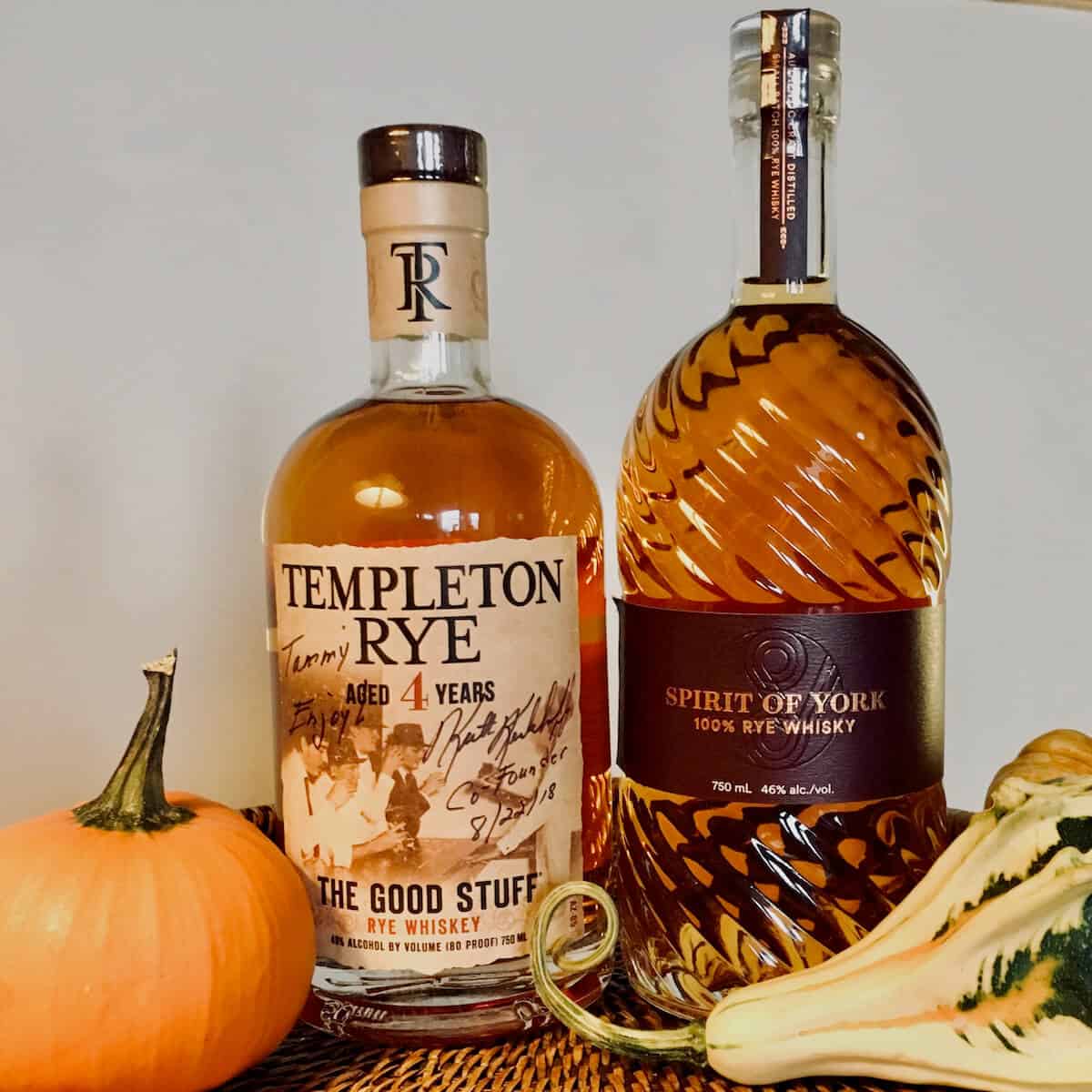 Templeton Rye whiskey and Spirit of York rye bottles surrounded by gourds on a wood tray.