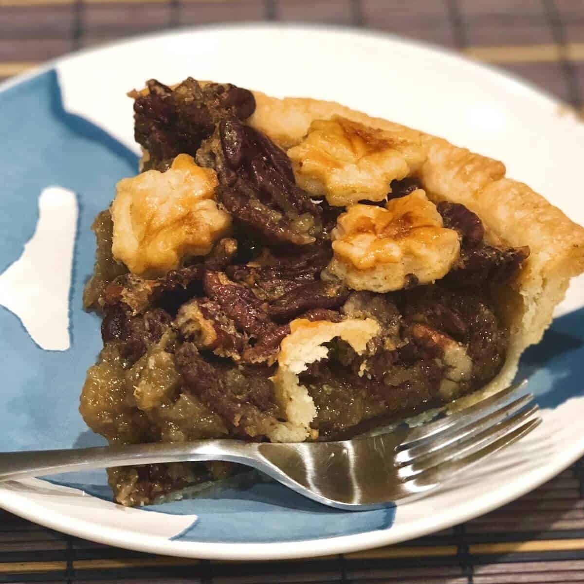 Maple Bourbon Pecan Pie slice on a blue & white plate and a fork.