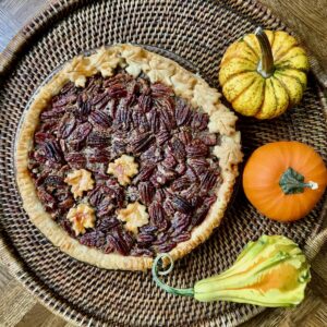 Pecan Pie on a wooden tray with gourds from overhead.