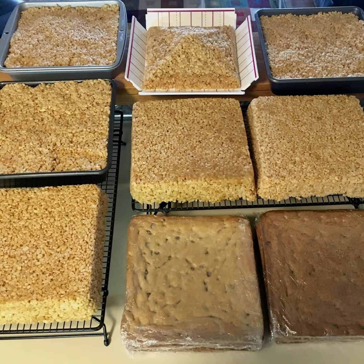 Prepared layers of crisped rice treats & chocolate chip cookie cake layers laid out on cooling racks.