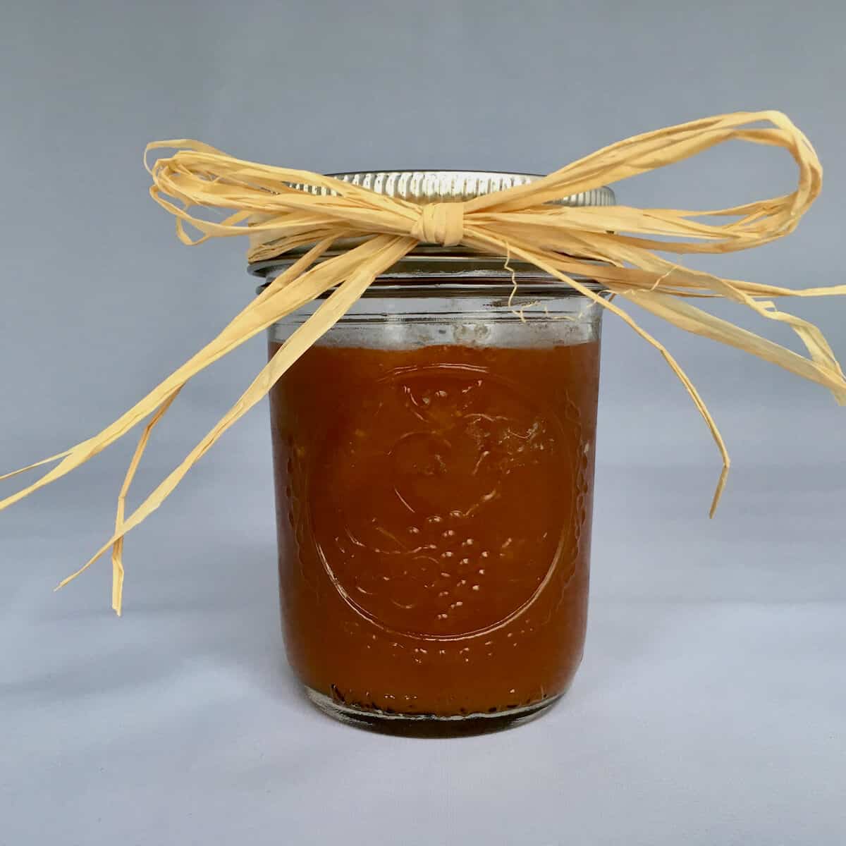 Whiskey Caramel Sauce in a jar tied with a raffia bow.