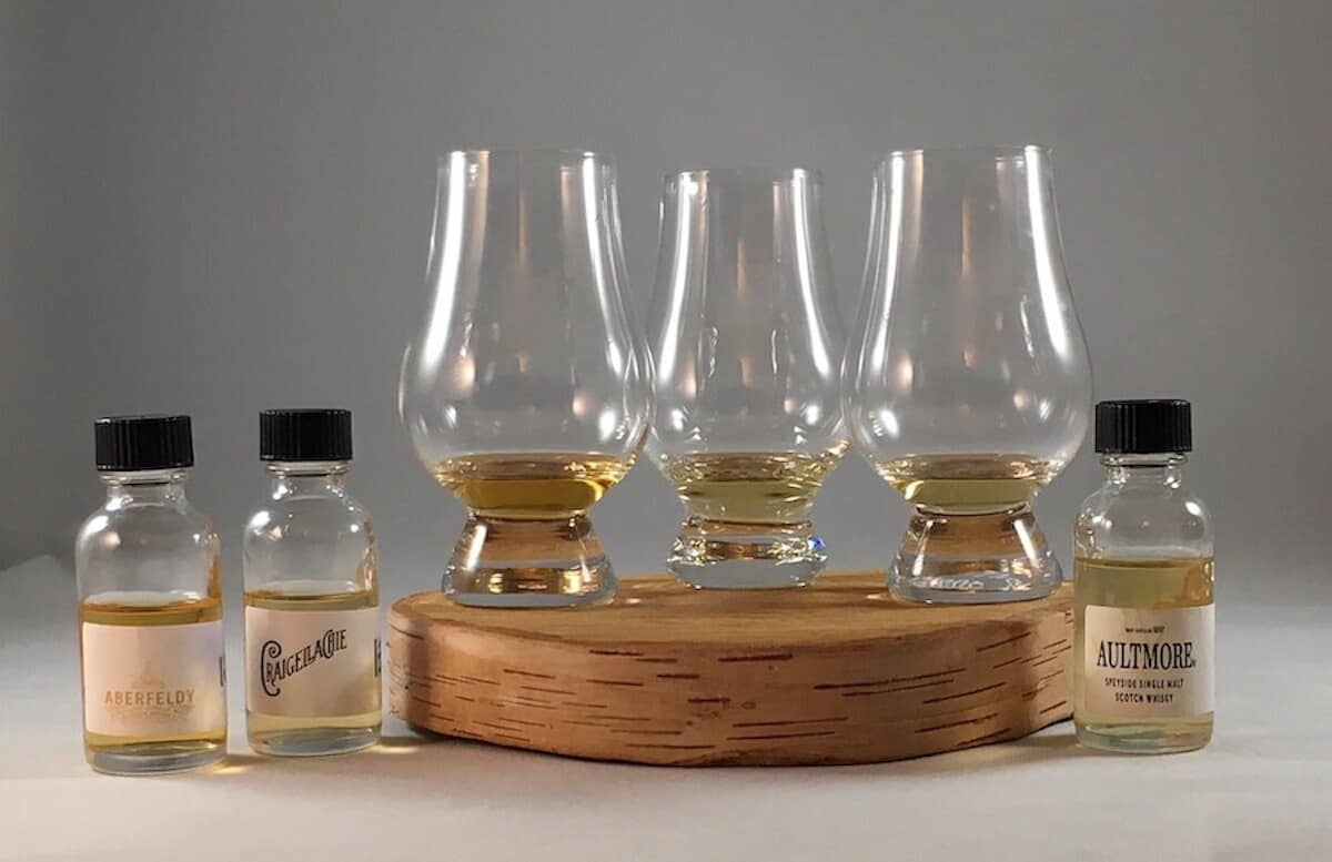 Aberfeldy, Craighellachie, Aultmore in sample bottles beside poured glasses on a wooden tray.