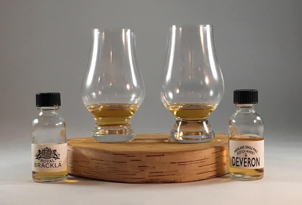 Royal Brackla & Deveron in sample bottles beside poured glasses on a wooden tray.