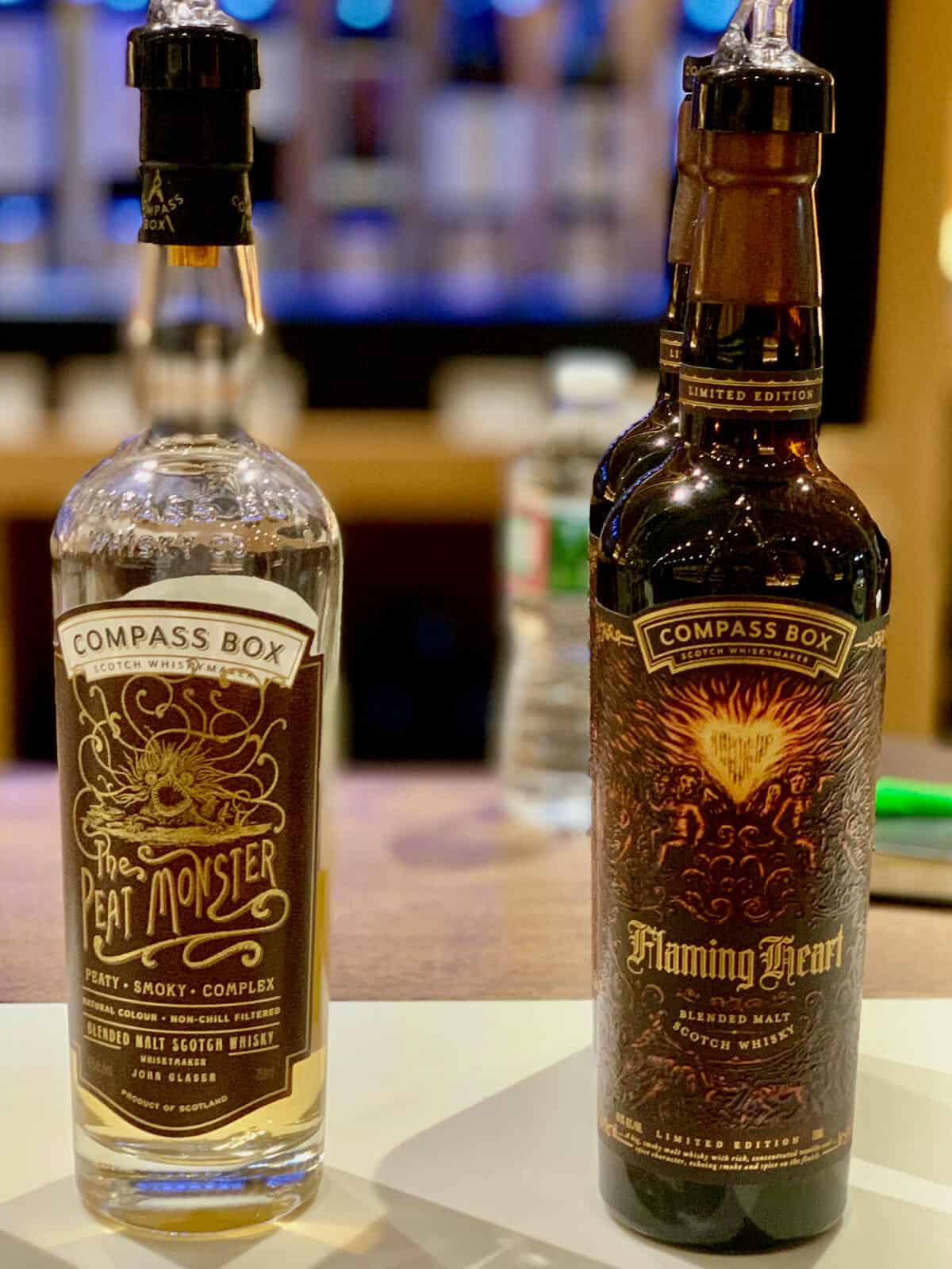 Compass Box Blended Scotch Peat Monster and Flaming Heart in bottles on a counter.