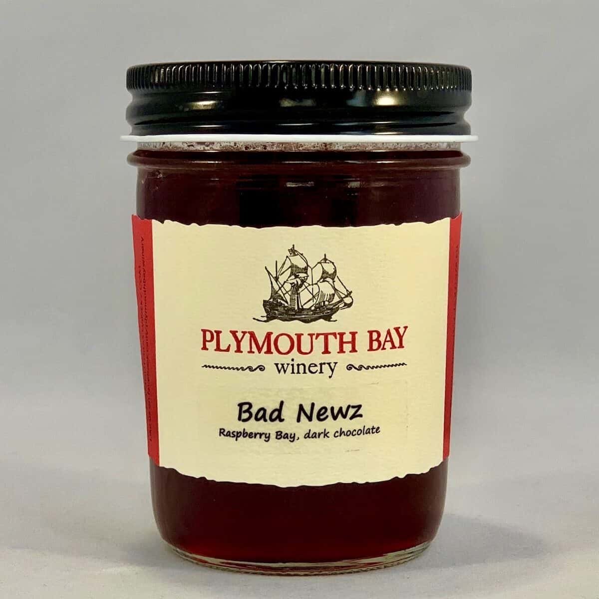 Jar of Plymouth Bay Winery's Bad Newz raspberry wine jelly on a counter.