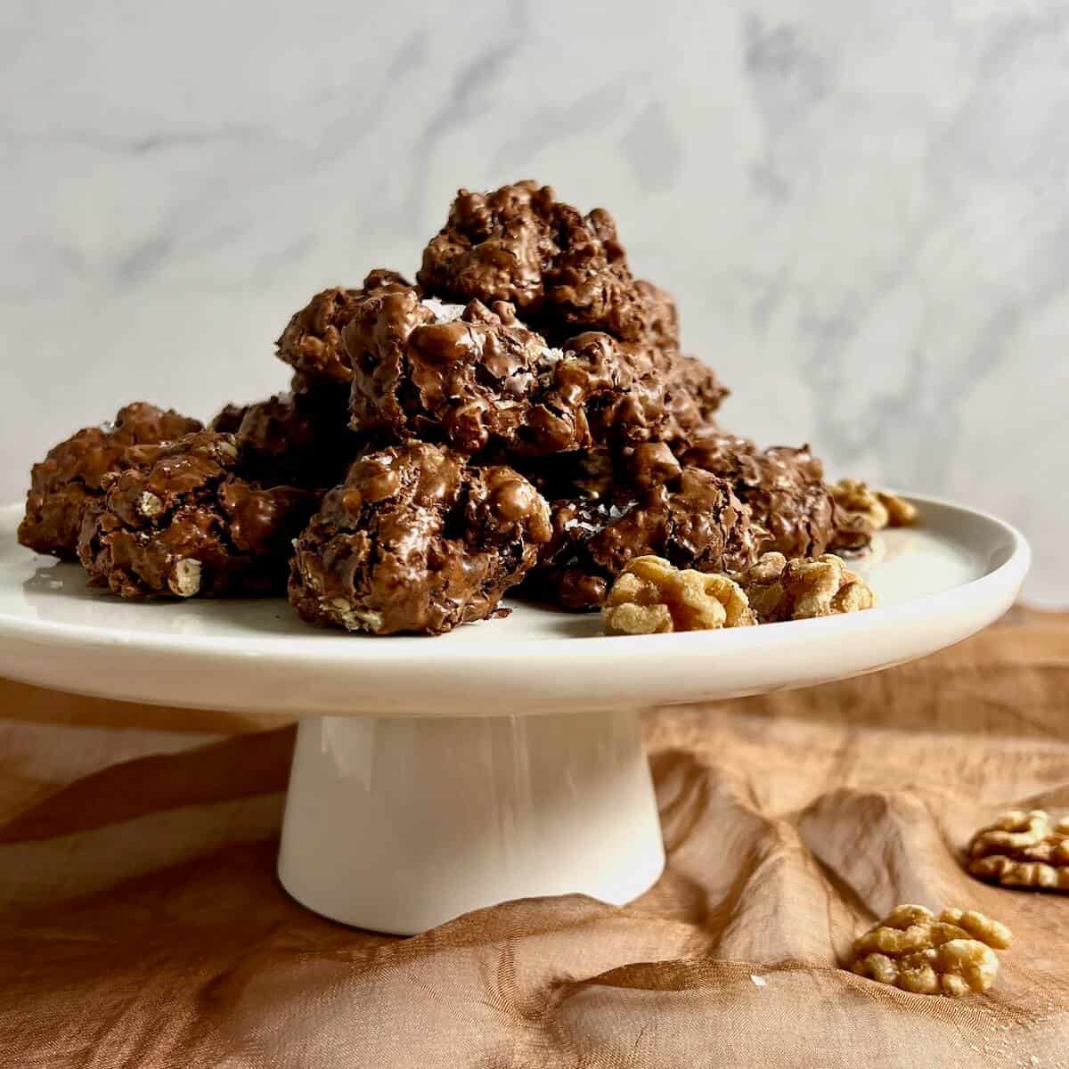 Flourless Chocolate Walnut Cookies piled on a white cake stand.