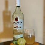 Daiquiri in a glass next to Bacardi Rum and a squeezed lime.