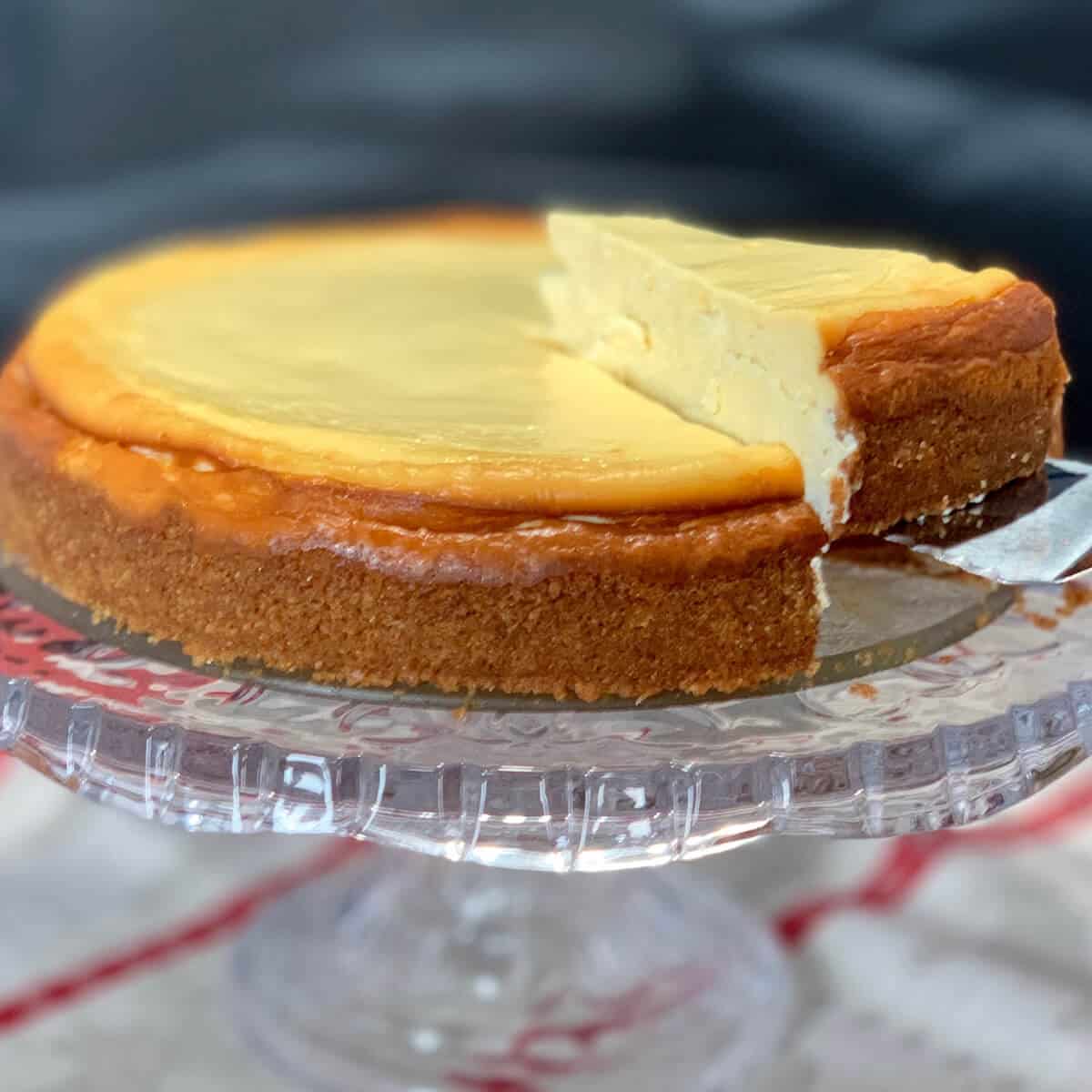 white wine cheesecake on cake plate with slice being lifted out.