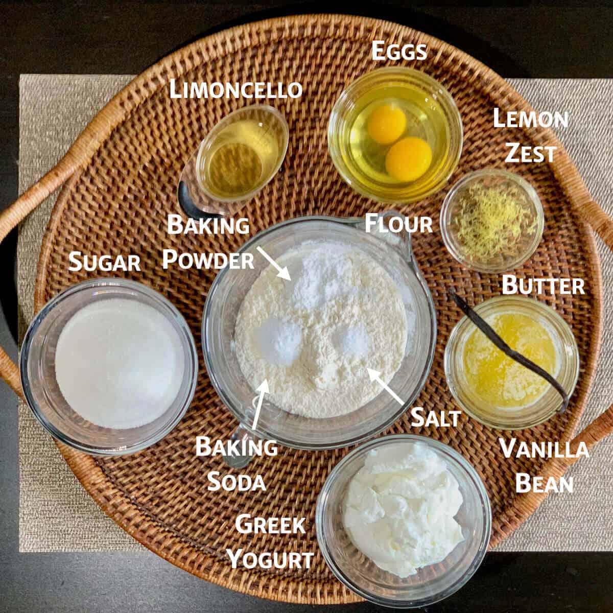Limoncello Cake ingredients portioned into glass bowls on a woven tray from overhead.