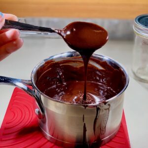 Dripping hot fudge sauce from spoon to saucepan.