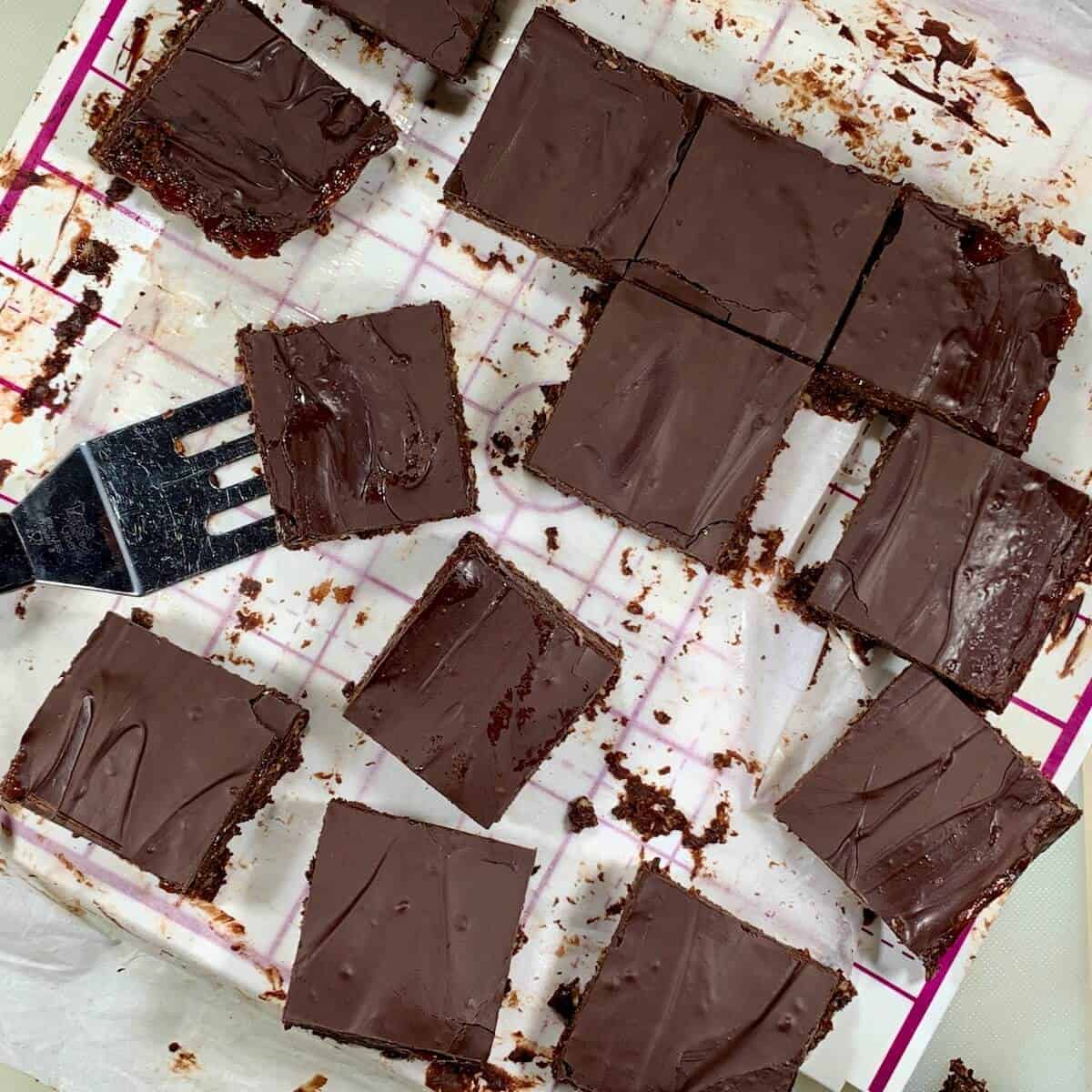 Cut chocolate raspberry brownies randomply placed on a pan with a small spatula.