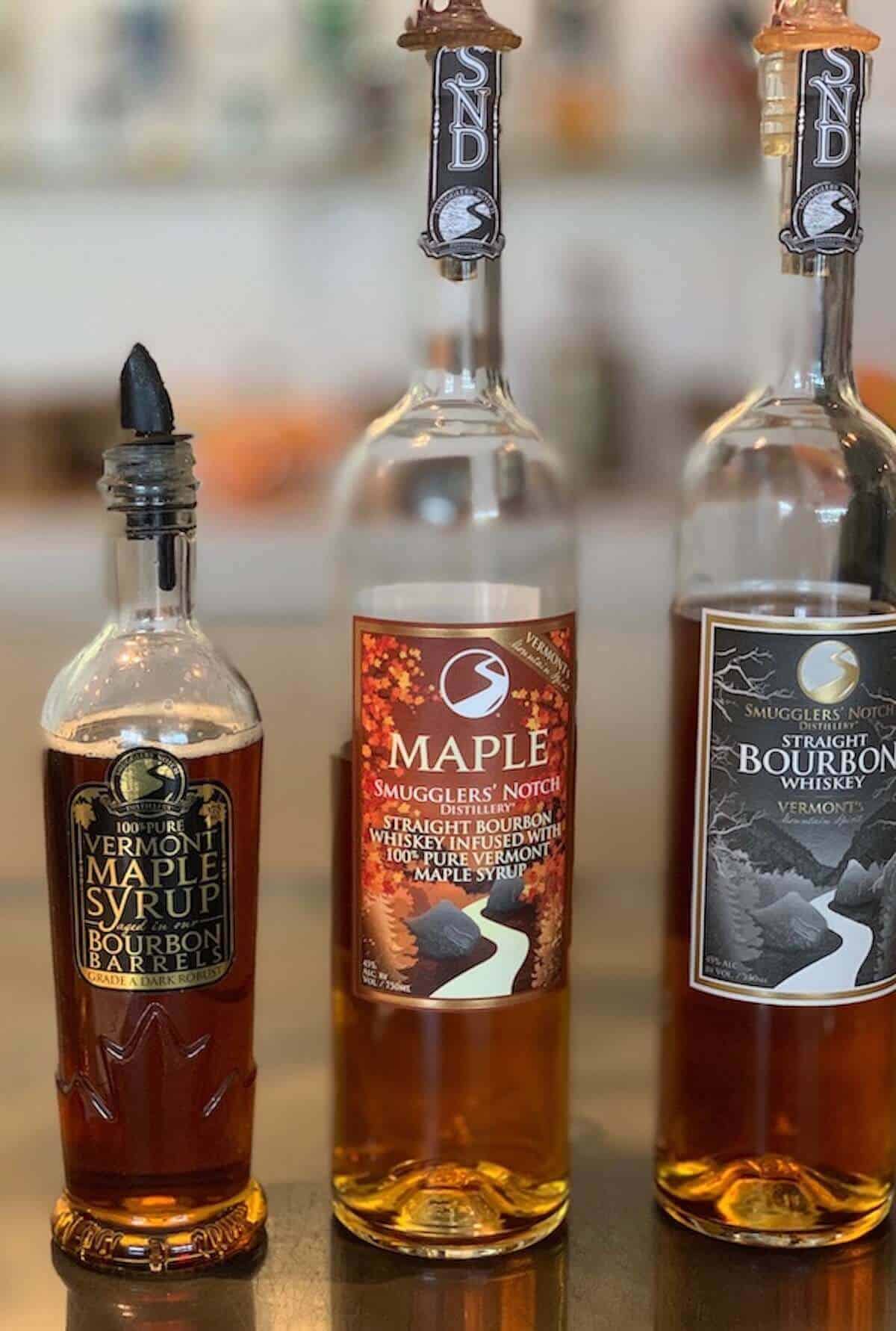 Smugglers' Notch Distillery maple syrup, maple bourbon, & straight bourbon on counter.