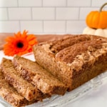 Sourdough Spice Cake sliced on glass plate with pumpkins.
