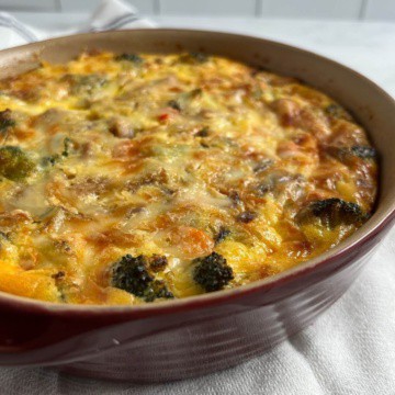Baked crustless quiche with sausage & broccoli in a round red baking dish.
