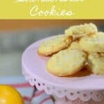 Lemon shortbread piled on a pink cake stand with lemons on a towel Pinterest banner..