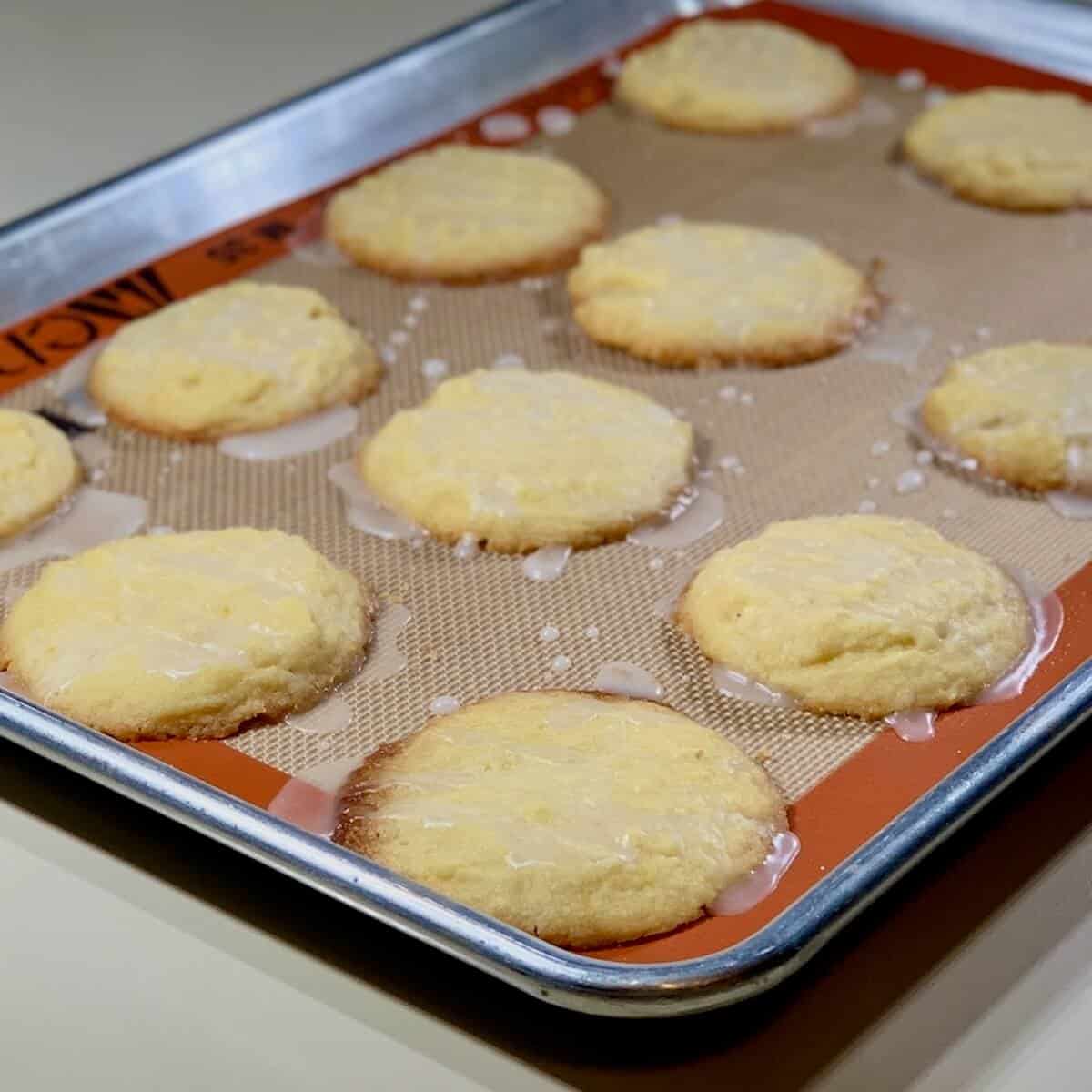 Glazed lemon shortbread cookies on a baking pan.