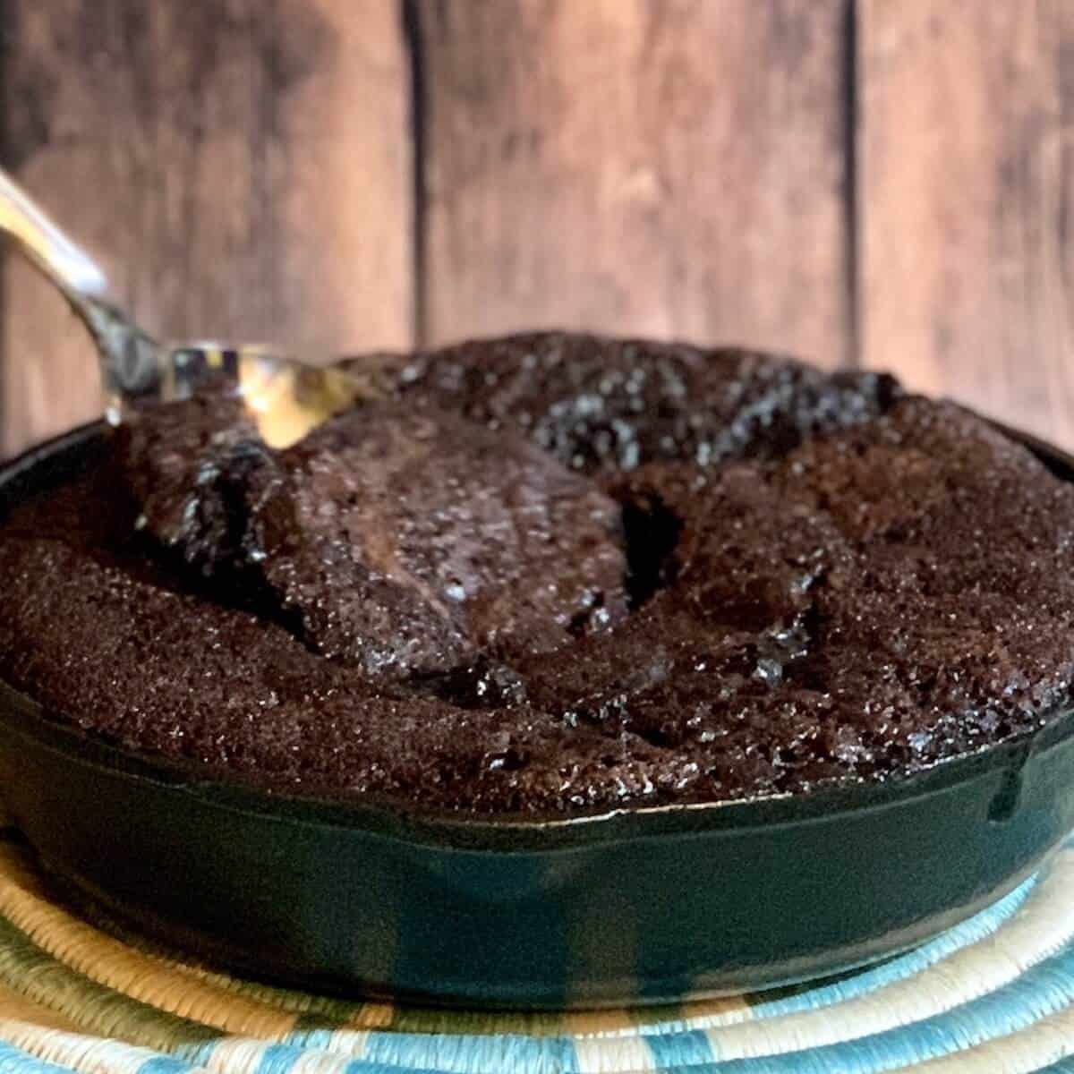 Hot Fudge Pudding Cake in a skillet with spoon lifting a bite.