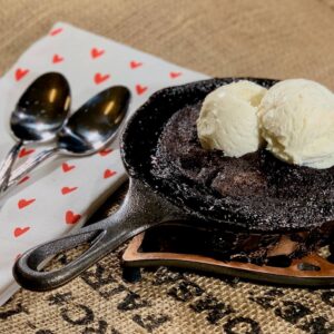 Hot Fudge Pudding Cake in a mini skillet with ice cream next to spoons.