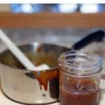 Caramel sauce in jar in front of a saucepan on a counter Pinterest banner.