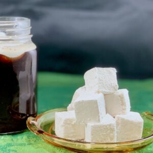 Irish Whiskey marshmallows stacked on a yellow plate with coffee in background.