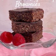 Three Chocolate Raspberry Brownies & fresh raspberries stacked on a glass stand on a pink scarf Pinterest banner.