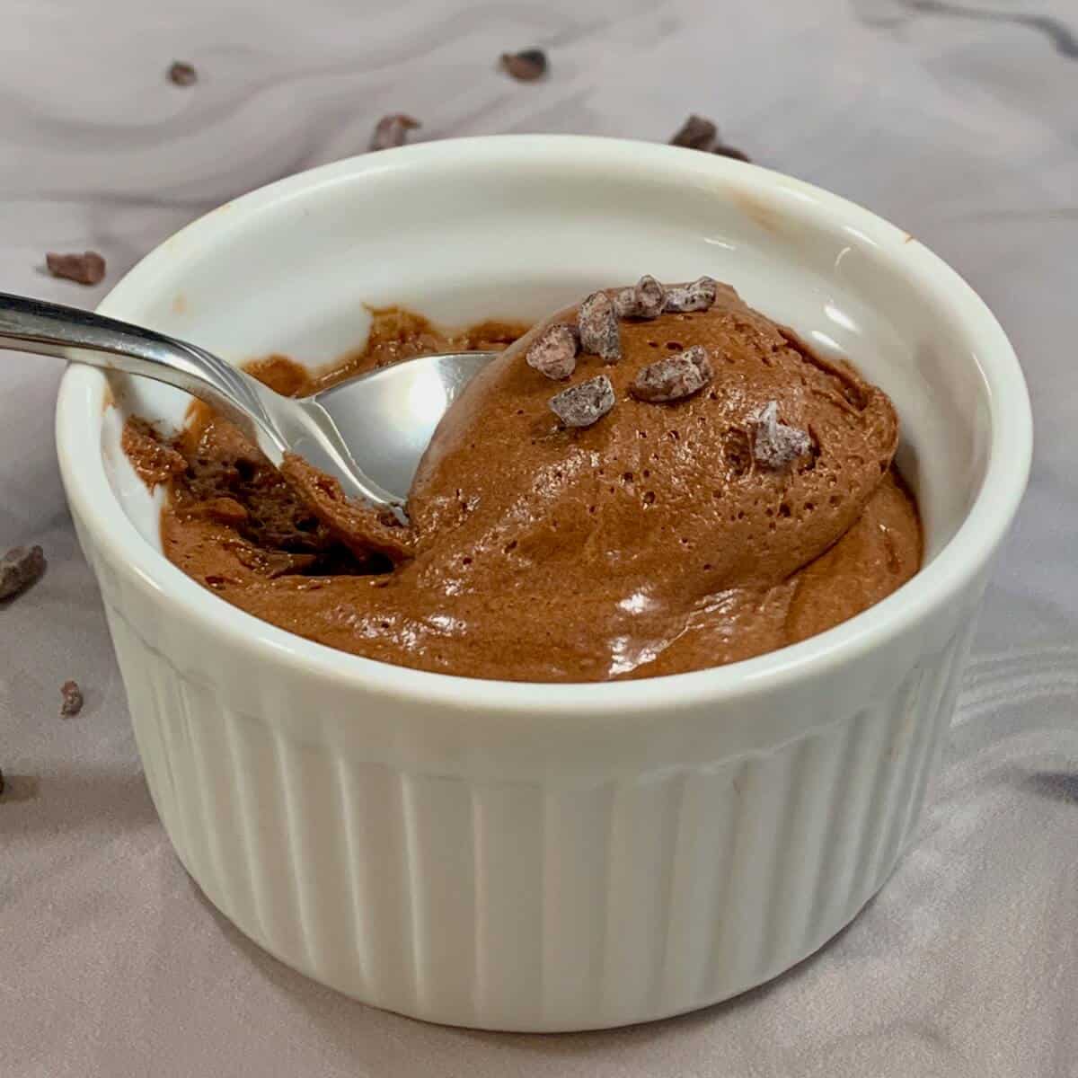 Closeup of Dairy-Free Chocolate Mousse lifted with a spoon from a white ramekin.