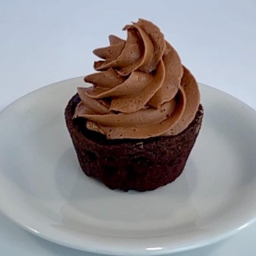 One eggless chocolate cake frosted with chocolate buttercream on a white plate.