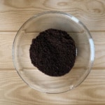 Chocolate cookie crumbs in a glass bowl from overhead.