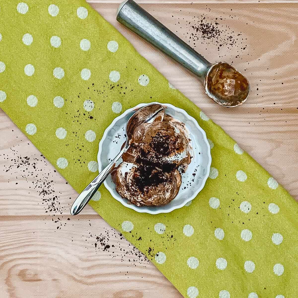 Chocolate Mint Marshmallow Ice Cream in a white bowl with spoon on a green towel from overhead.