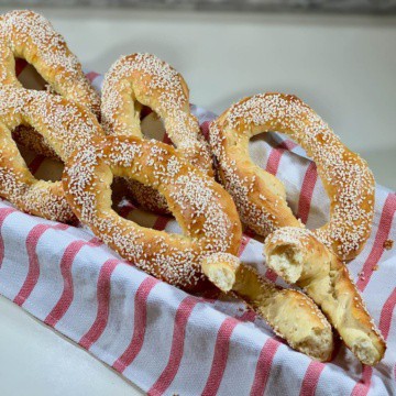 Sourdough Jerusalem Bagels with one broken in half in a basket lined with a red & white striped towel.